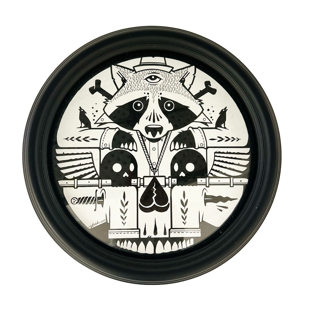 Framed circular painting of a black and white painting of a raccoon holding two skulls in black frame
