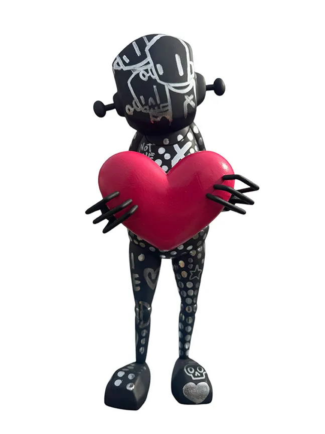 front view of a black and silver robot statue covered in designs holding a red heart