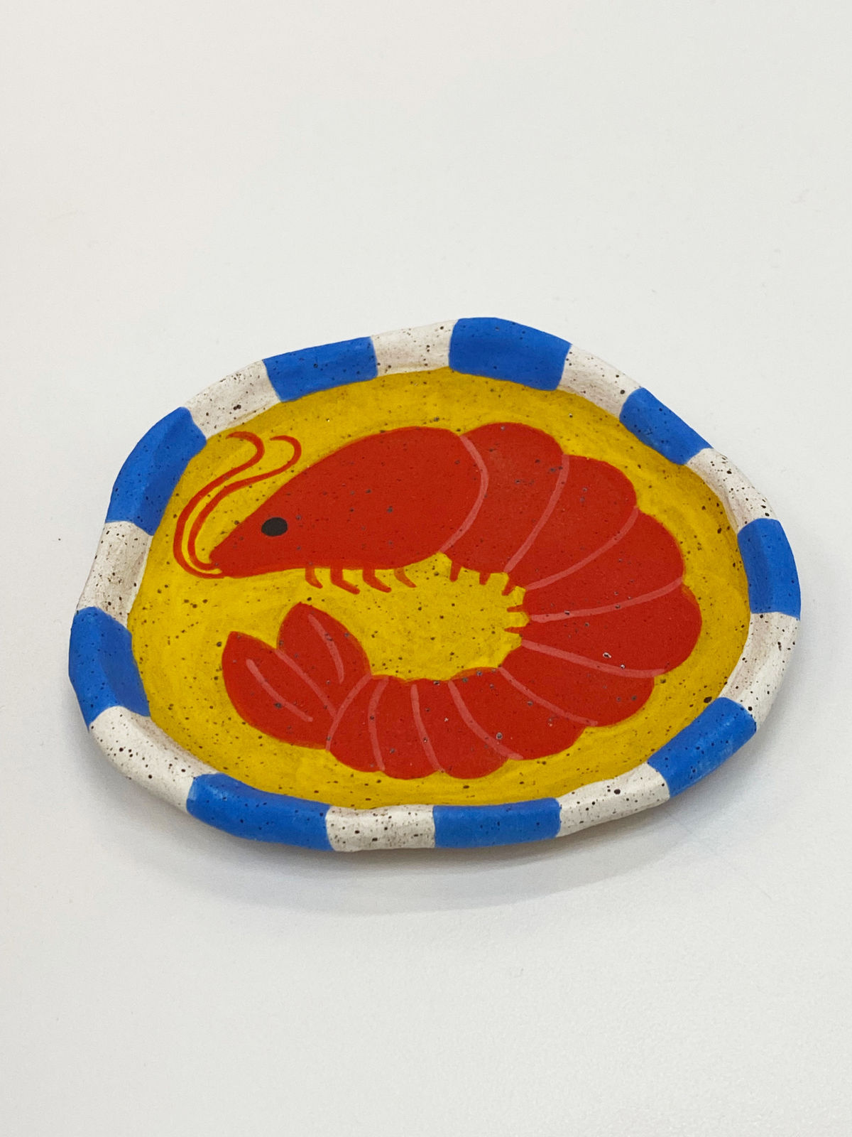 Jackie Brown ceramic plate of shrimp on yellow background with blue and white striped border