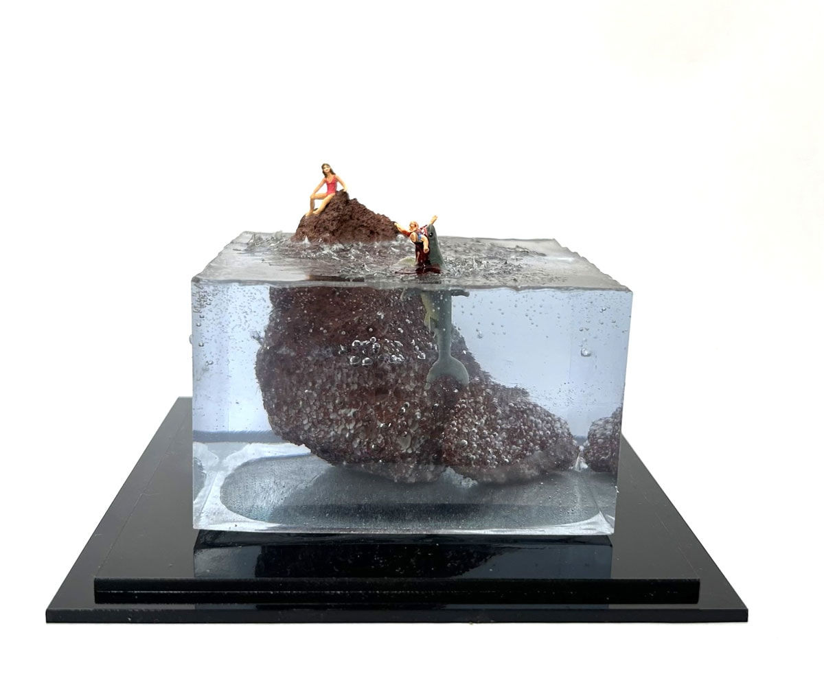 sculpture of a woman on a rock and another woman being eaten by a shark in the water