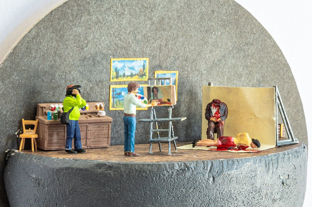 Miniature diorama by Abigail Goldman of a man painting a portrait of two dead bodies while another man is filming