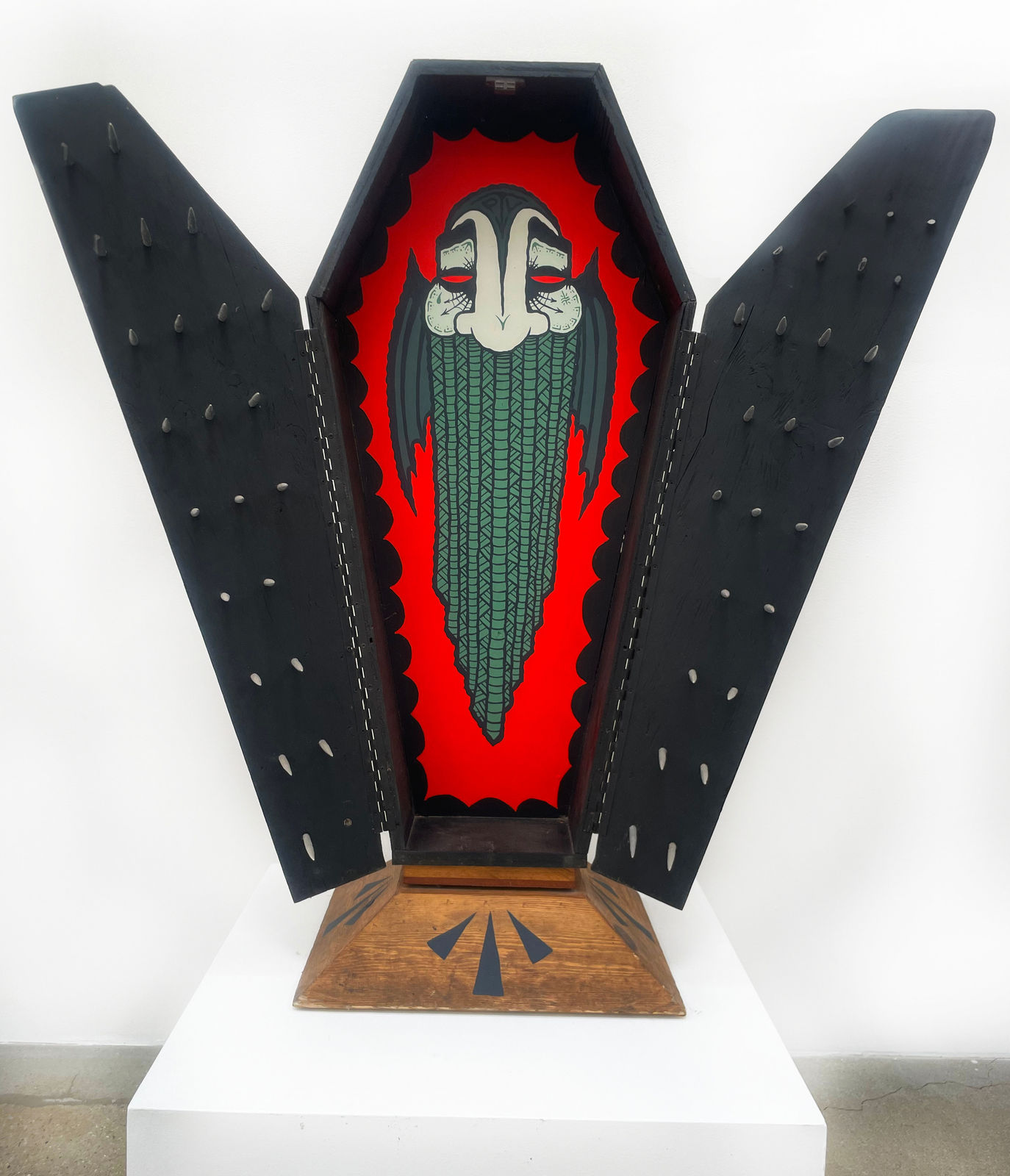 Open coffin with black doors and painted vampire on red background on inside