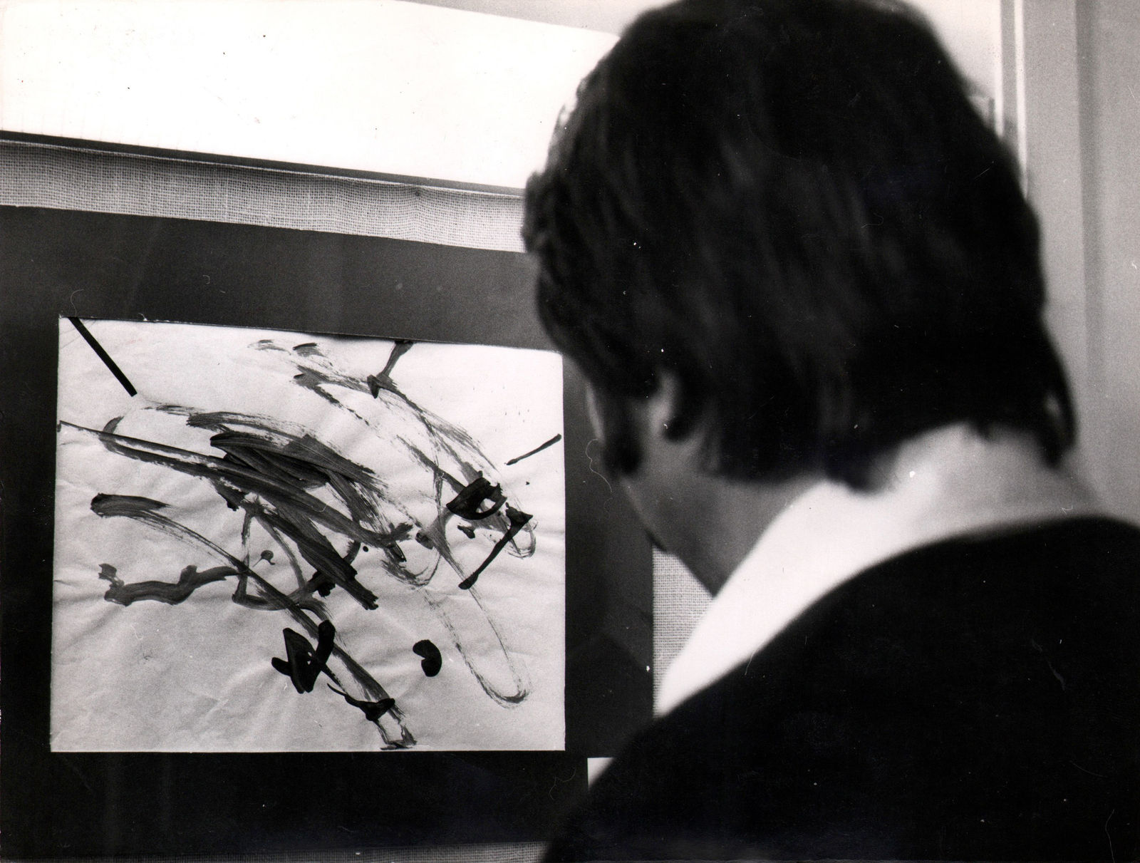Back of mans head as he looks at painting done by chimpanzee