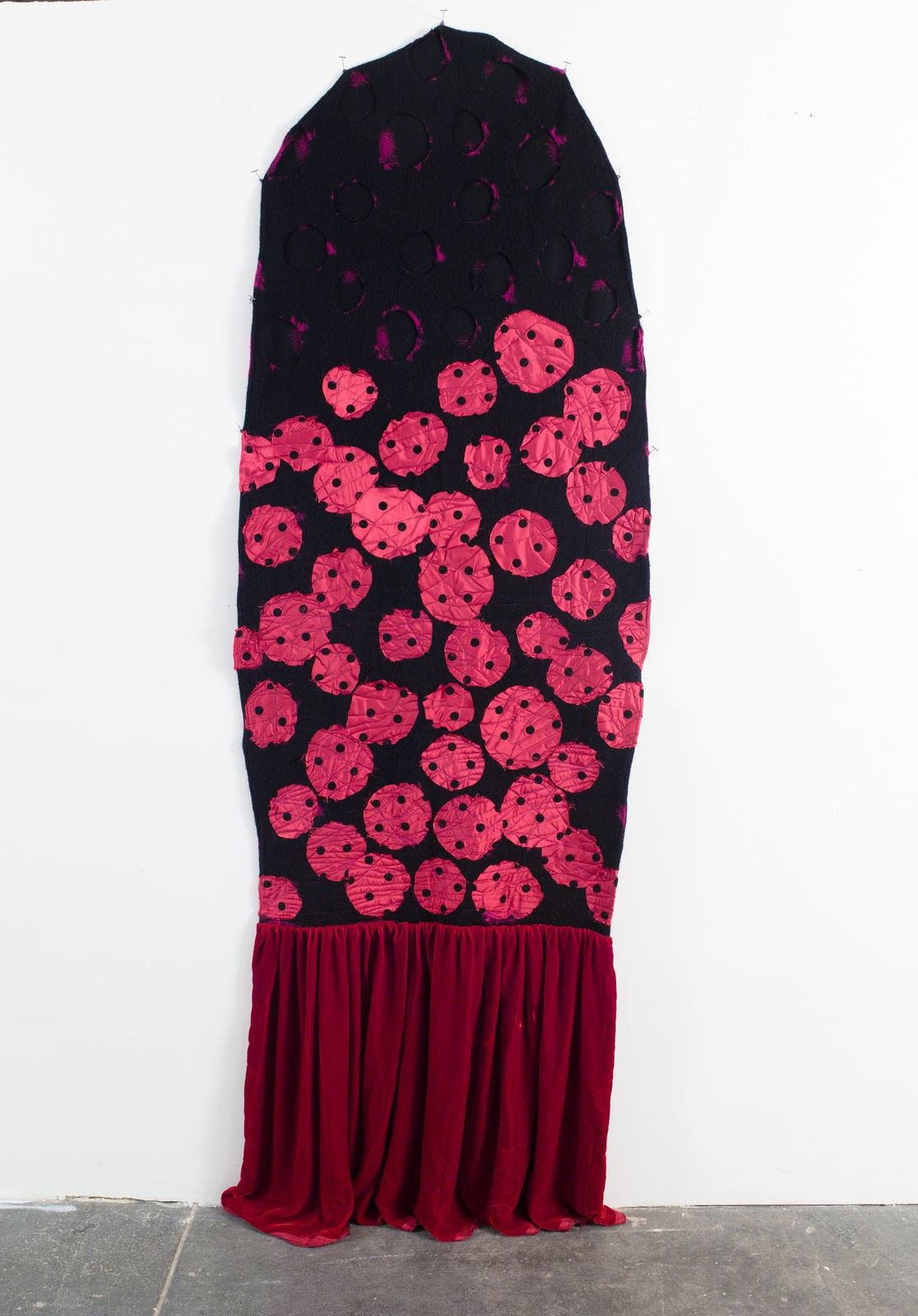 Abstract fabric portrayal of a black ghost with pink dots and a red skirt