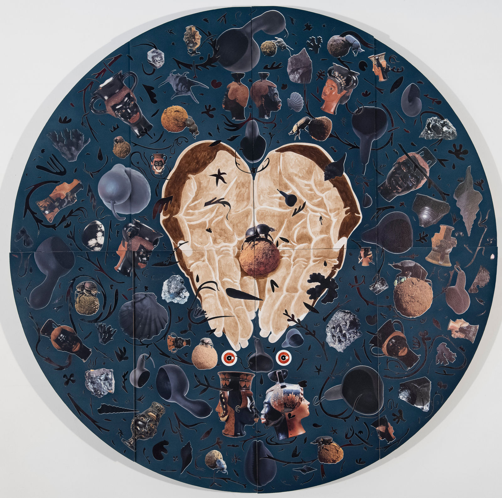 Blue velvet tondo with hands in the middle holding a dung beetle, surrounded by archeological objects