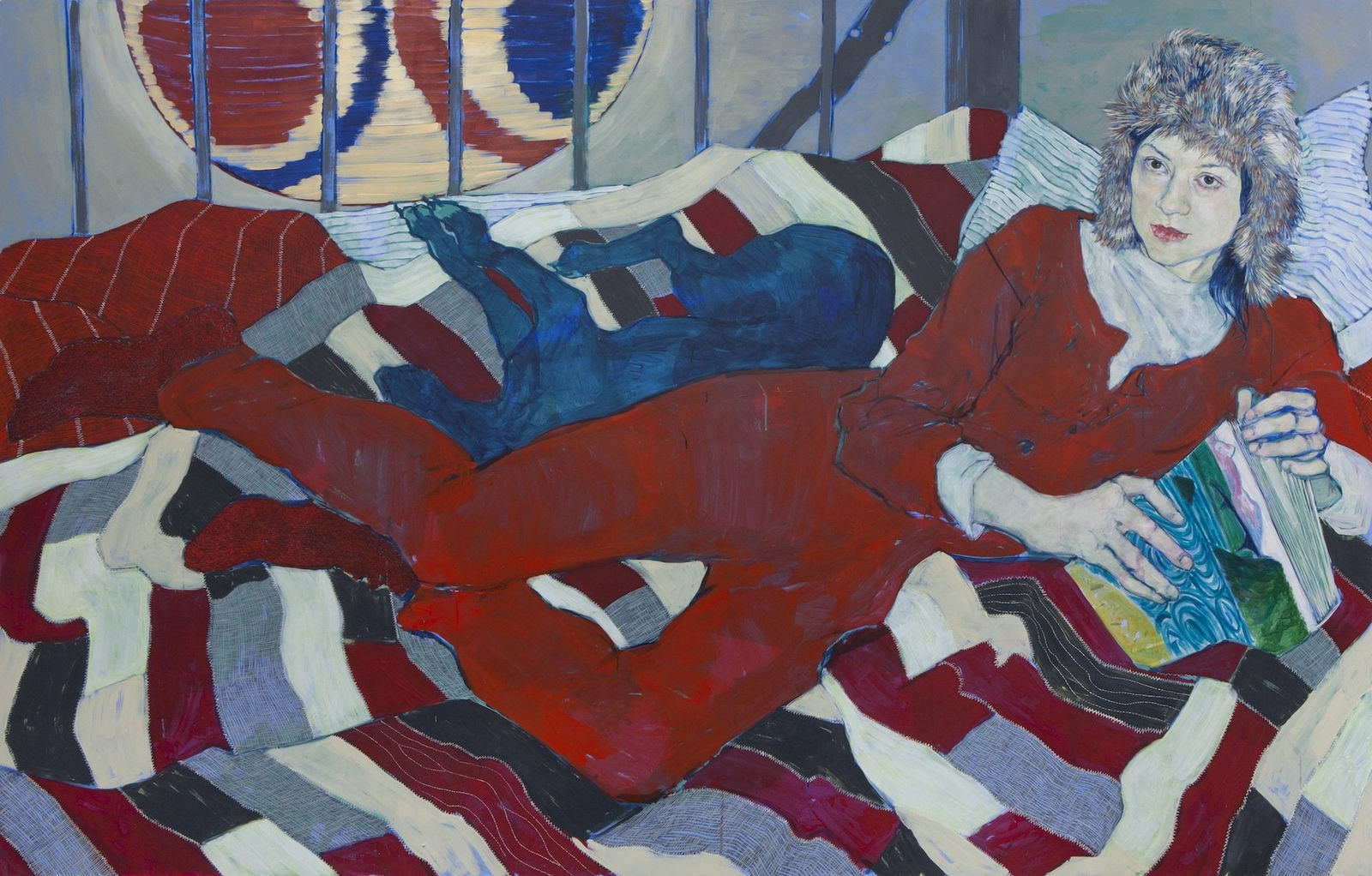 Woman in red outfit lounges on striped quilt