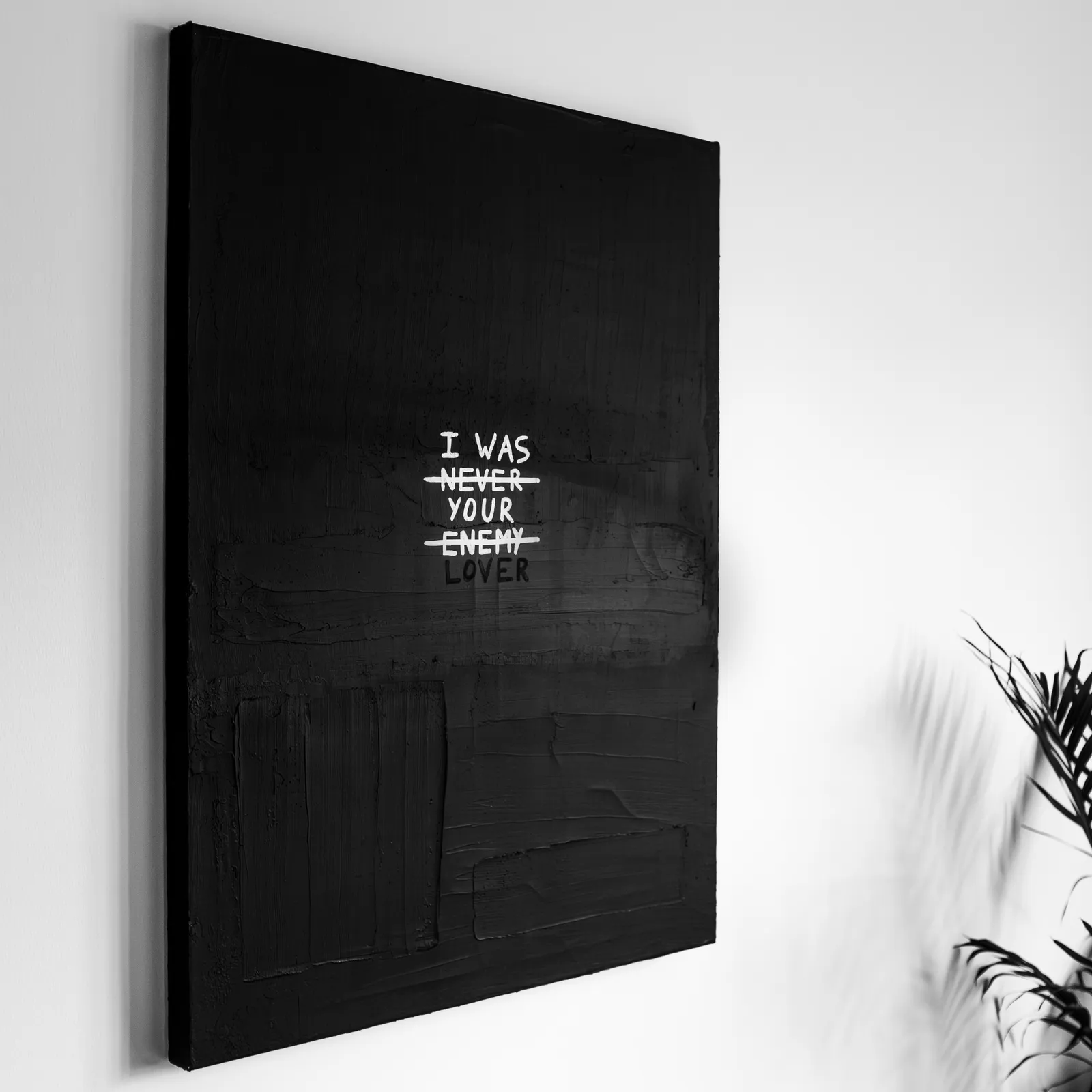 A close-up perspective shot of the artwork showing the high-contrast white lettering against the heavily textured black joint compound, capturing the raw and emotional feel of the piece.