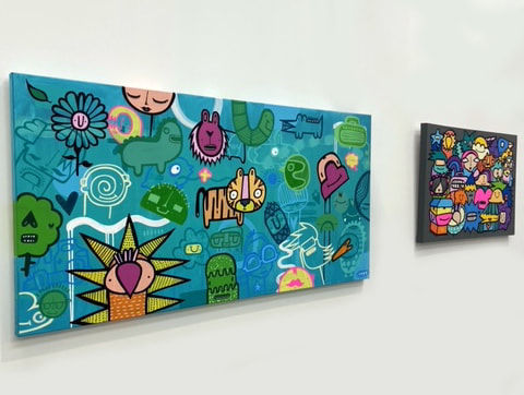 Two cartoon street style art landscape painting hung on gallery wall