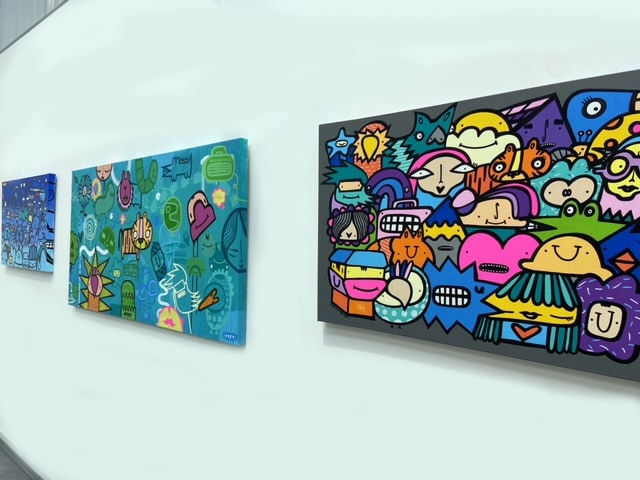 Three cartoon street style art landscape painting hung on gallery wall
