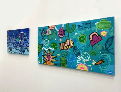 Two cartoon street style art landscape painting hung on gallery wall