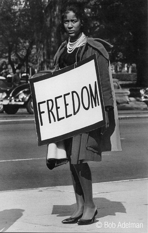Black & white photograph of African-American woman carrying a sandwich board with the word “Freedom”