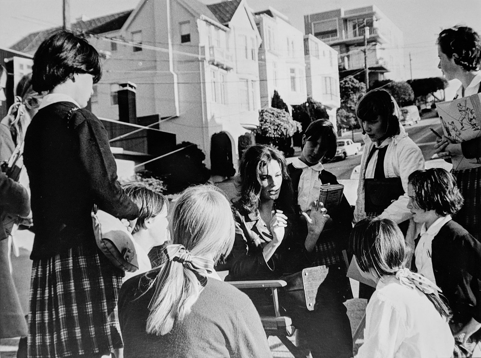 Black and white photograph of Jacqueline Bissett outside talking to a group of schoolgirls, on the set of “Bullitt”