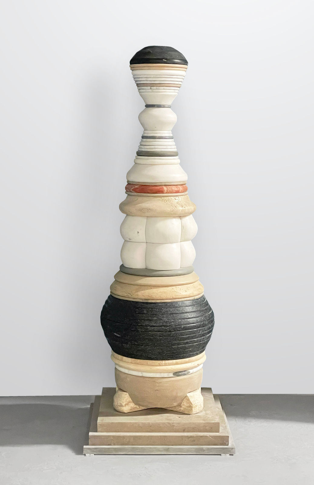Human-scale totemic sculpture comprising varied layers of carved marble and stone
