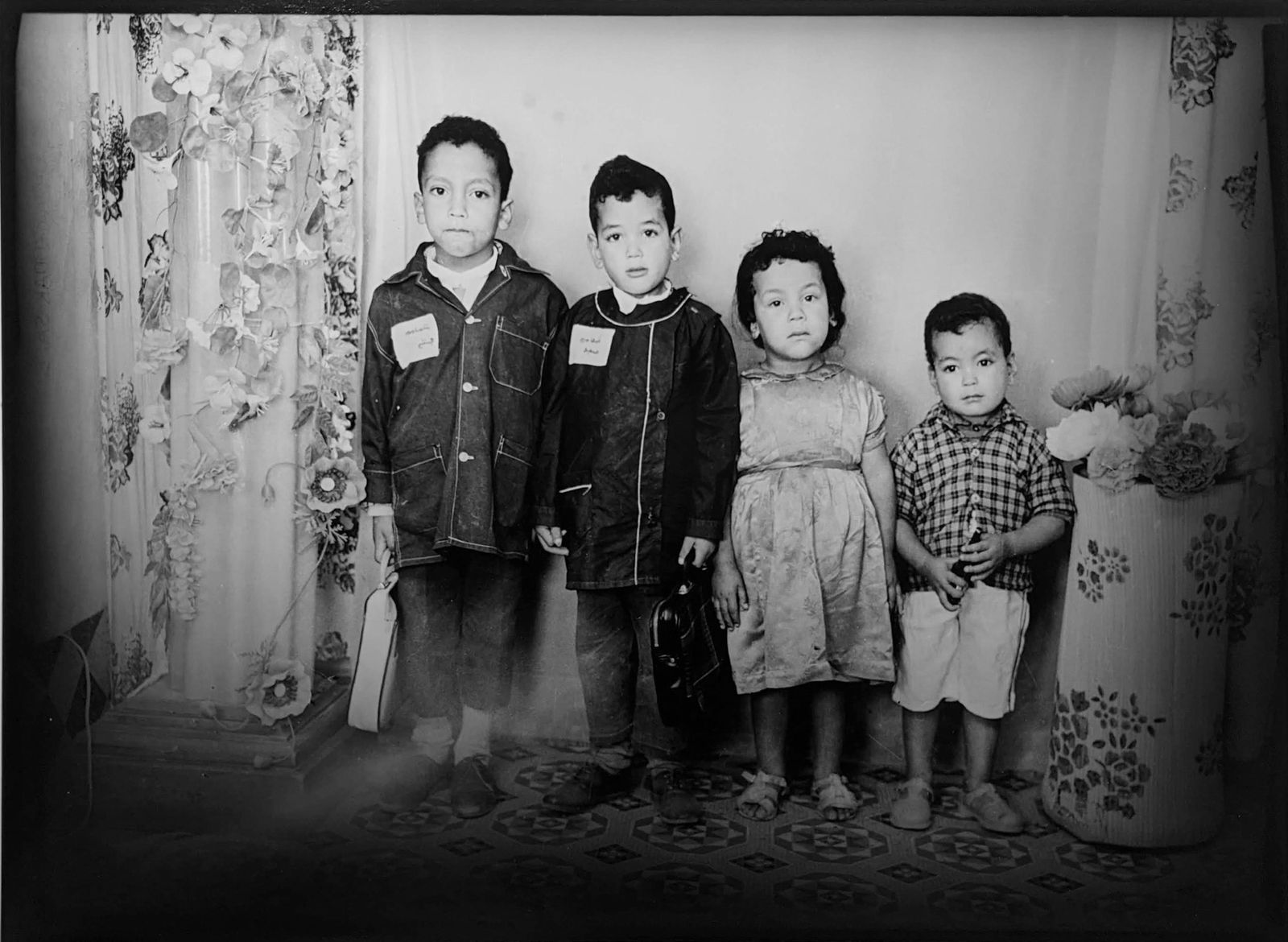 1960s black and white photograph of four young boys standing in a row from tallest to shortest