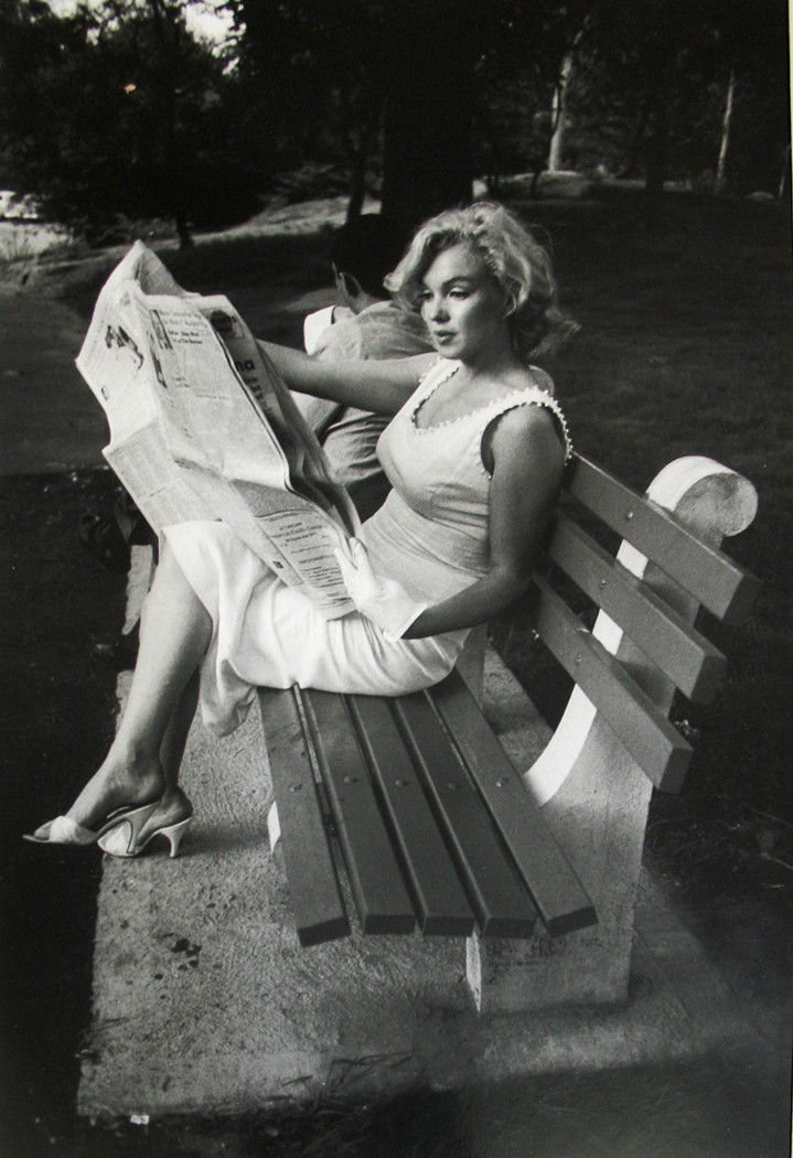 Marilyn Monroe in white dress reading a newspaper on a Central Park bench in New York City, 1956
