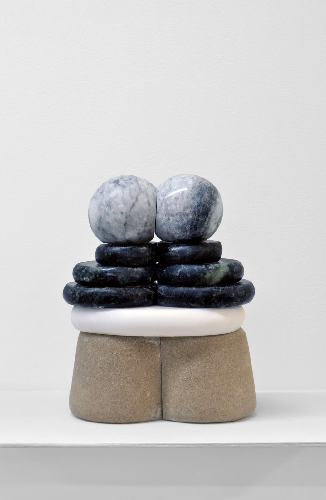 Minimalist sculpture made of stone and marble layers that resembles an artifact
