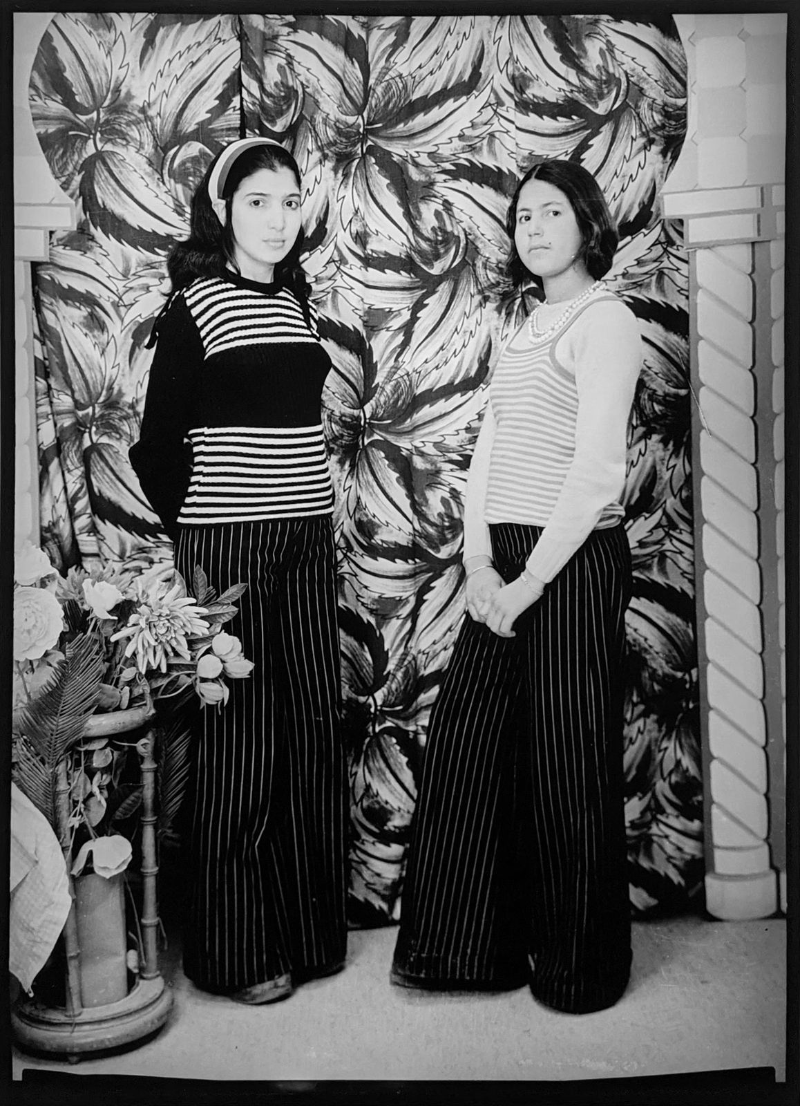 160s black and white photograph of two young women standing facing each other but looking at the camera