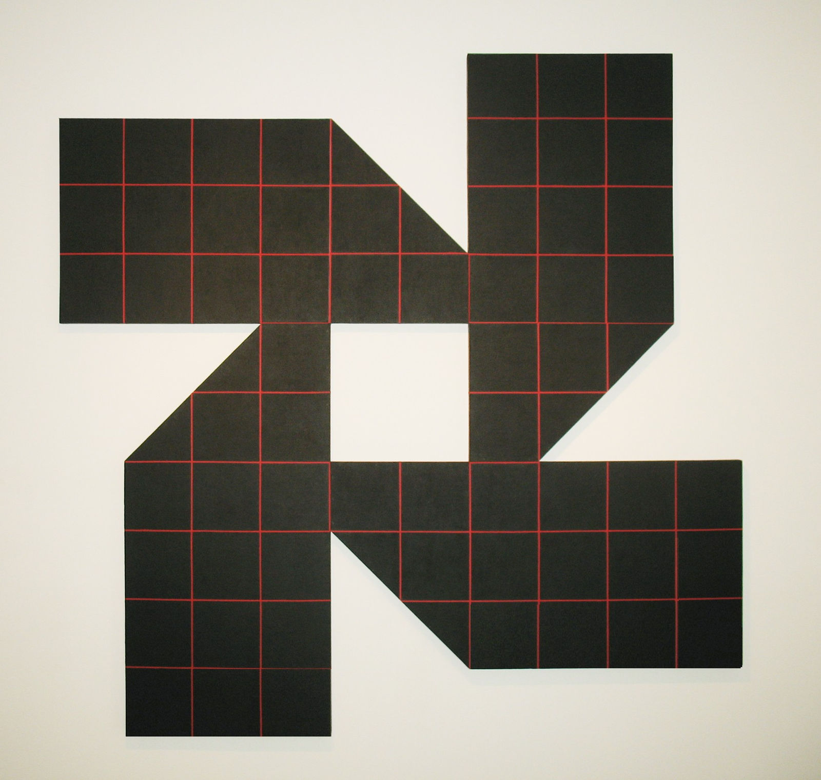 Acrylic painting on masonite of a shape formed by four identical black geometric shapes with red grid lines surrounding one small square of negative space