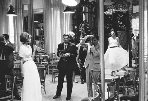 Black and white photograph of photographer Richard Avedon getting a closer look at the models after the August 1962 fashion show