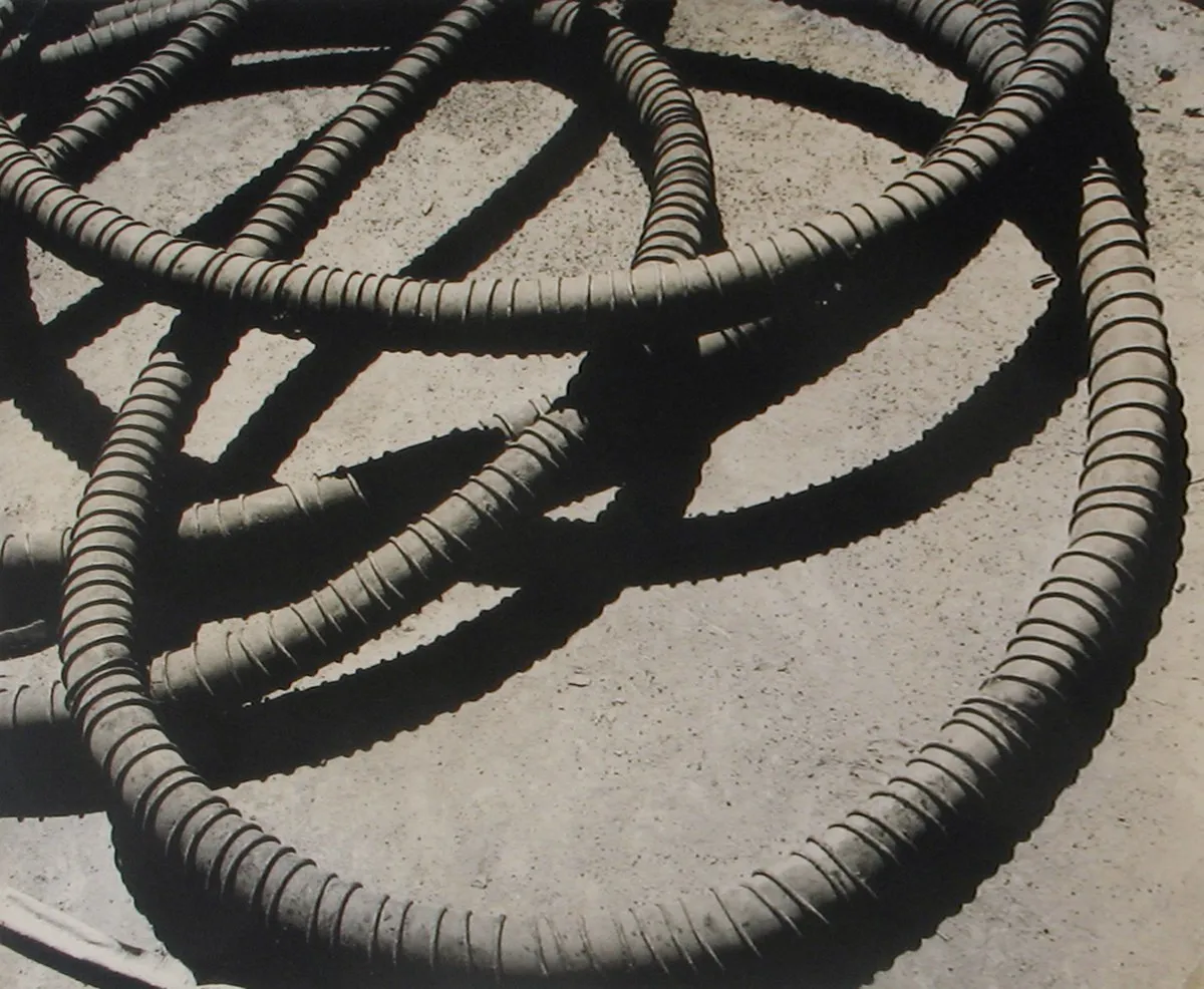 Black and white photograph of a metal coil and the shadows it casts against the ground