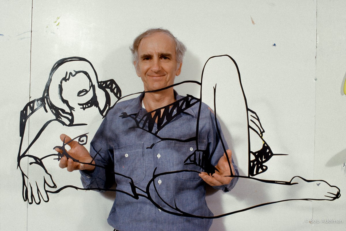 Photograph of Tom Wesselmann holding a steel laser-cut drawing of an outline of a female nude