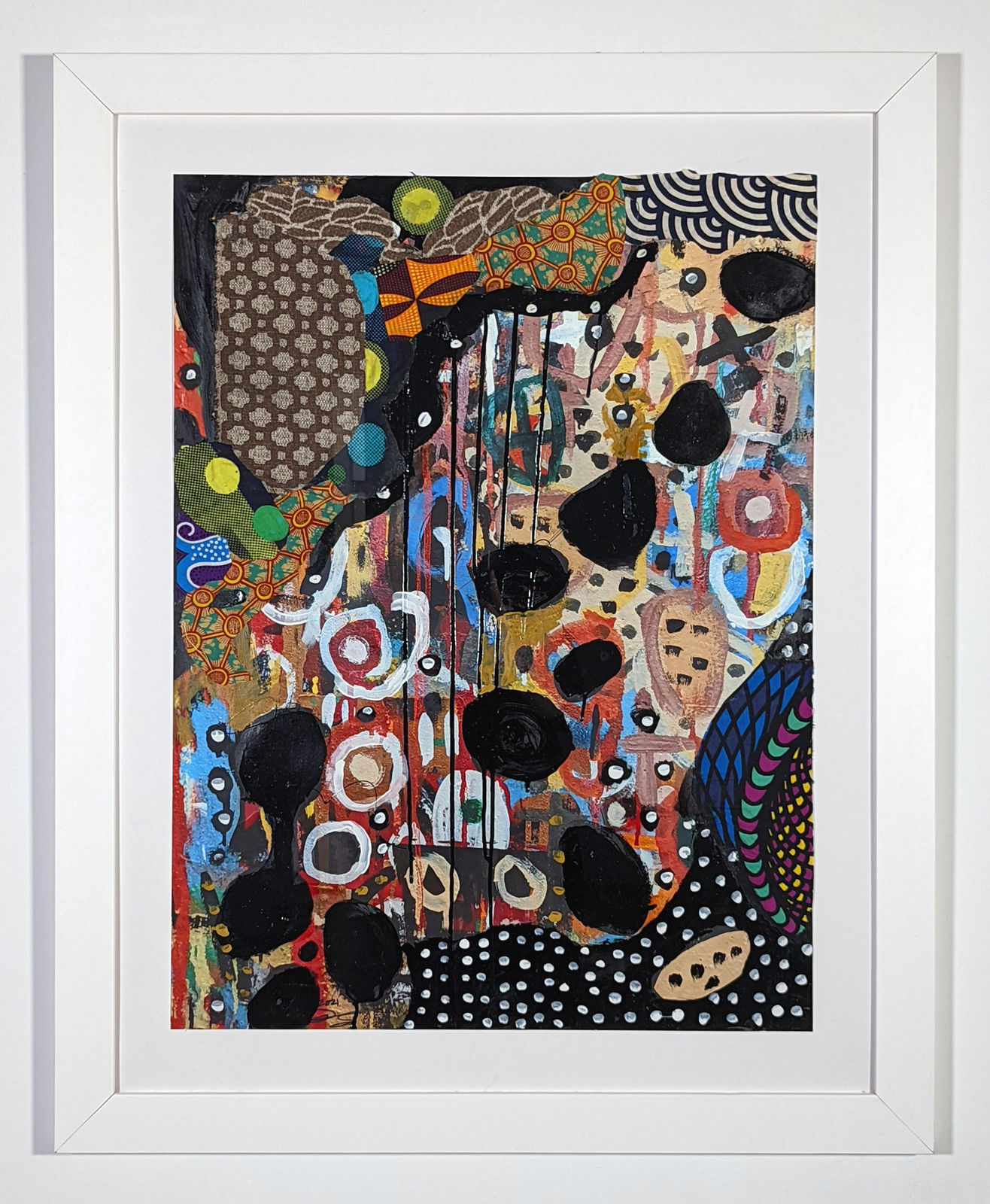 White framed colorful artwork comprised of oil and patterned fabric on print in a 
