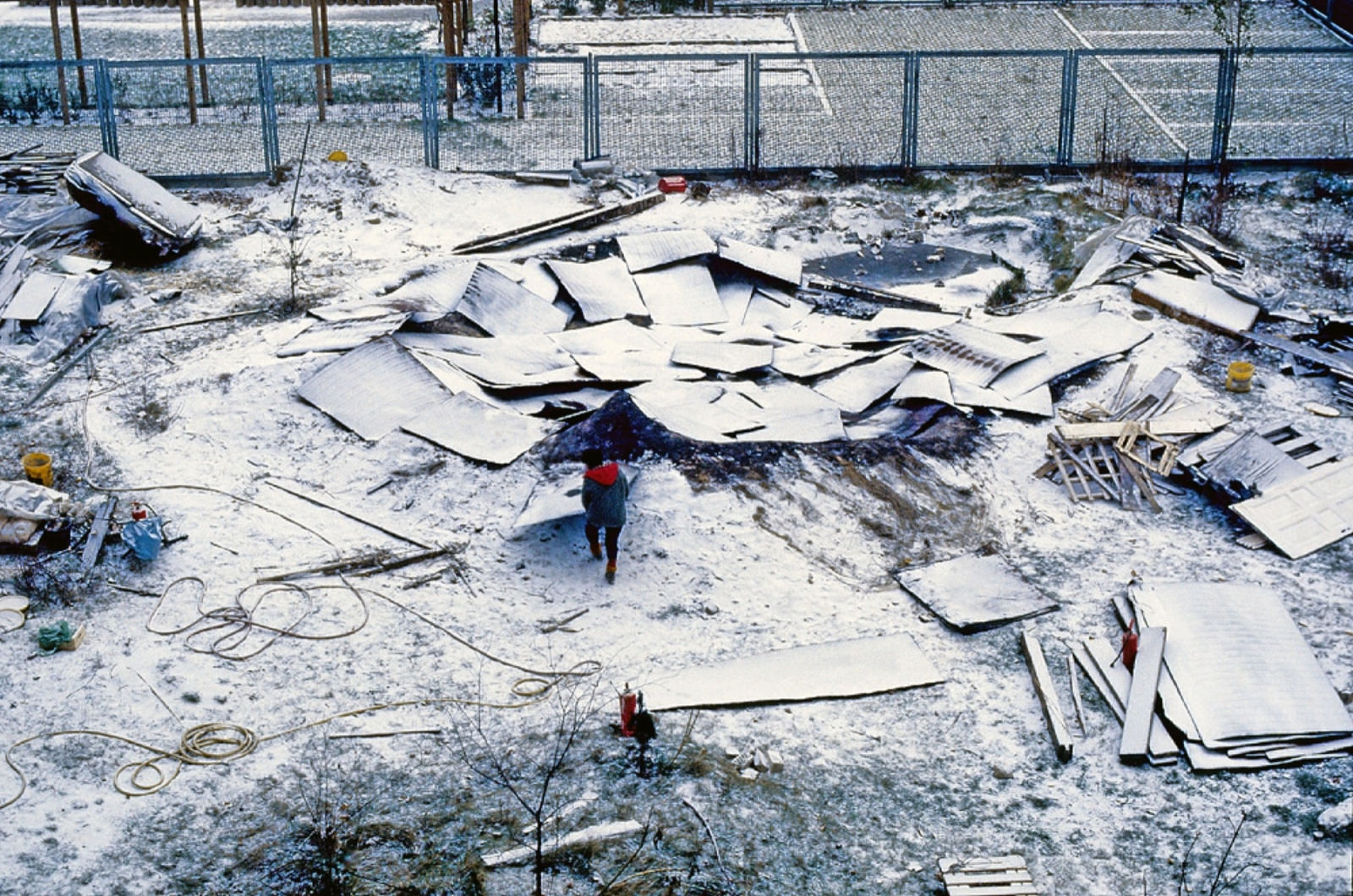 Photo of scattered pieces of wood covered in snow with a person in the centr
