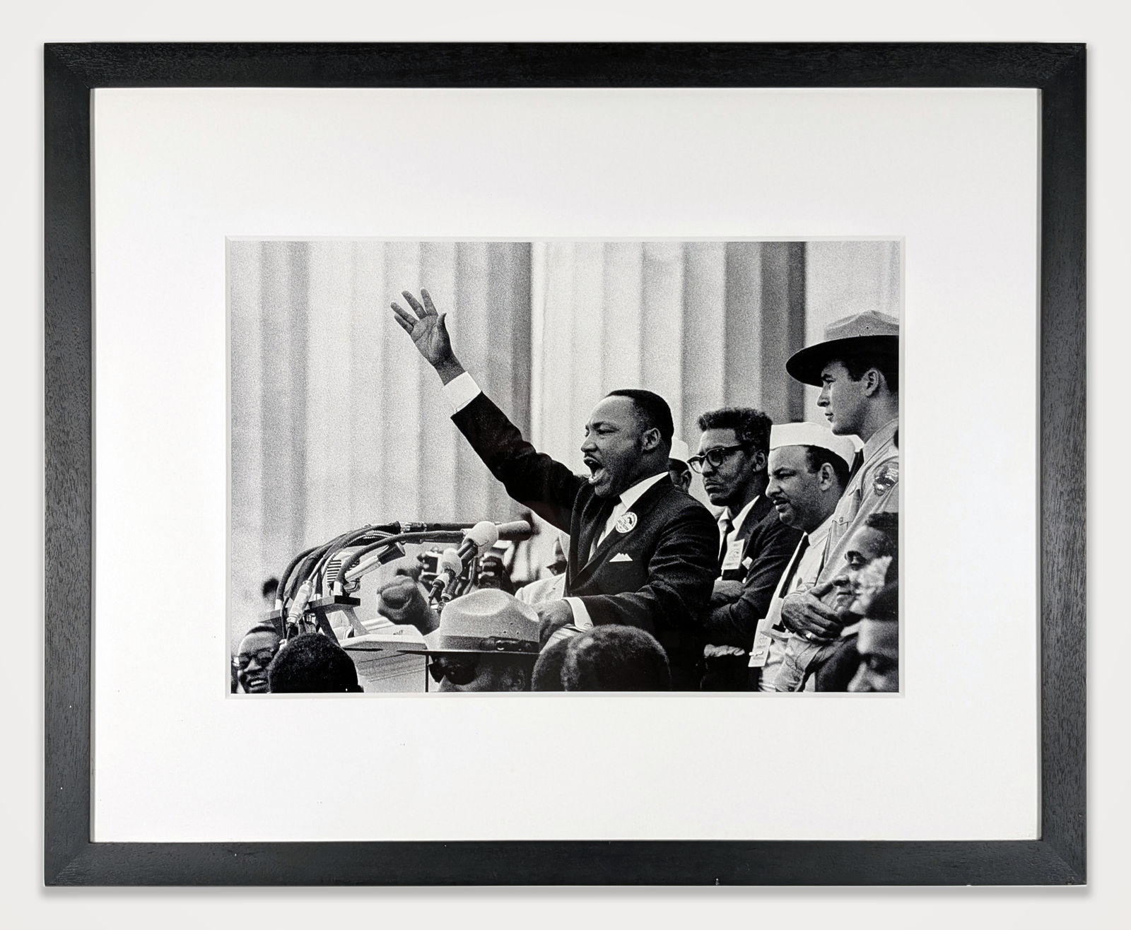 Framed black & white photograph of Martin Luther King Jr. speaking, right hand raised, people behind him visible