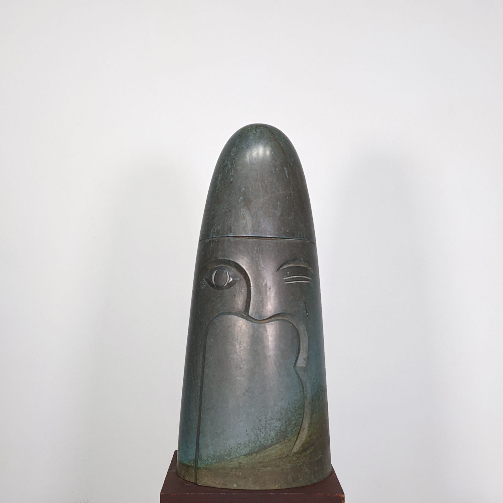 Modernist oxidized bronze sculpture of a stylized, cone-shaped head with a hat