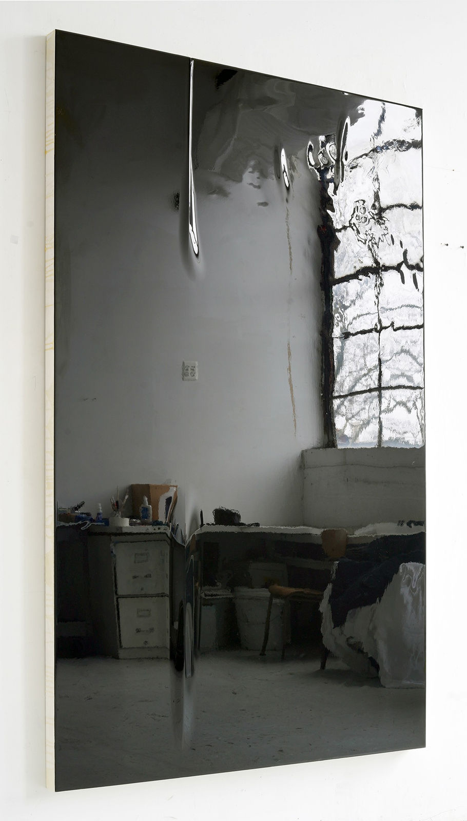 Angled view of a rectangular wood panel covered in reflective black urethane resin, black vinyl, and mixed media is mounted on a white wall