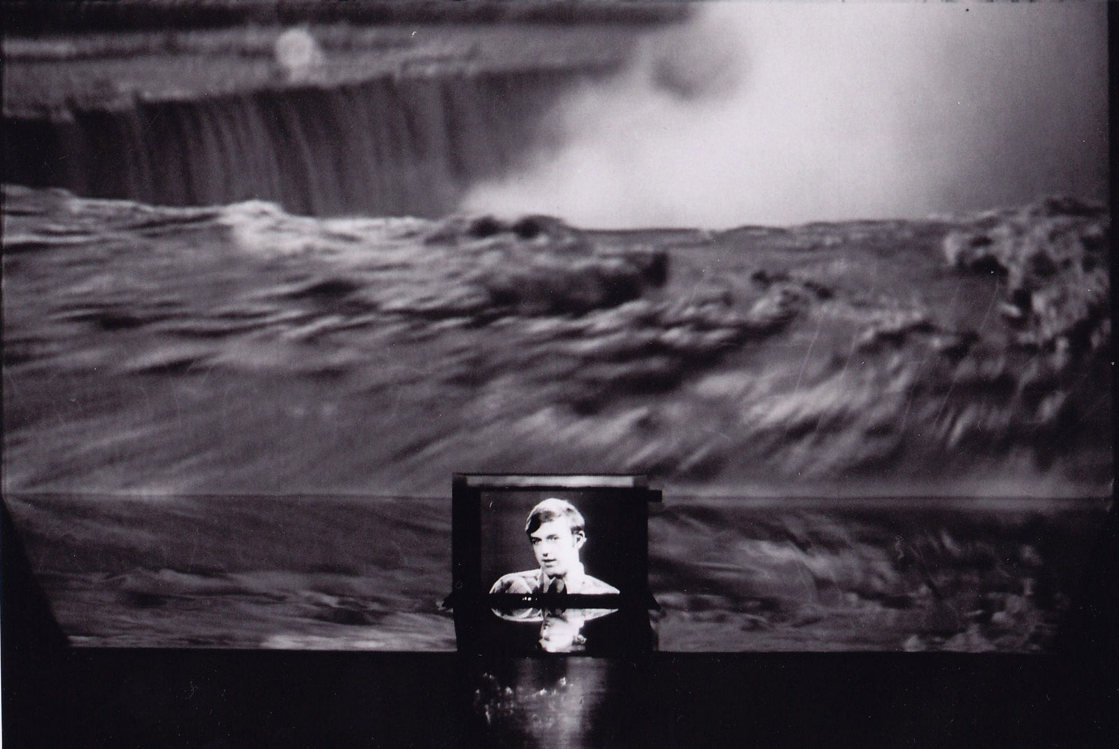 Installation of two videoes, one of a man speaking on a small television and one projected on a mirrored platform