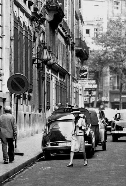 Black and white photograph of Designer Coco Chanel walking down her street in Paris
