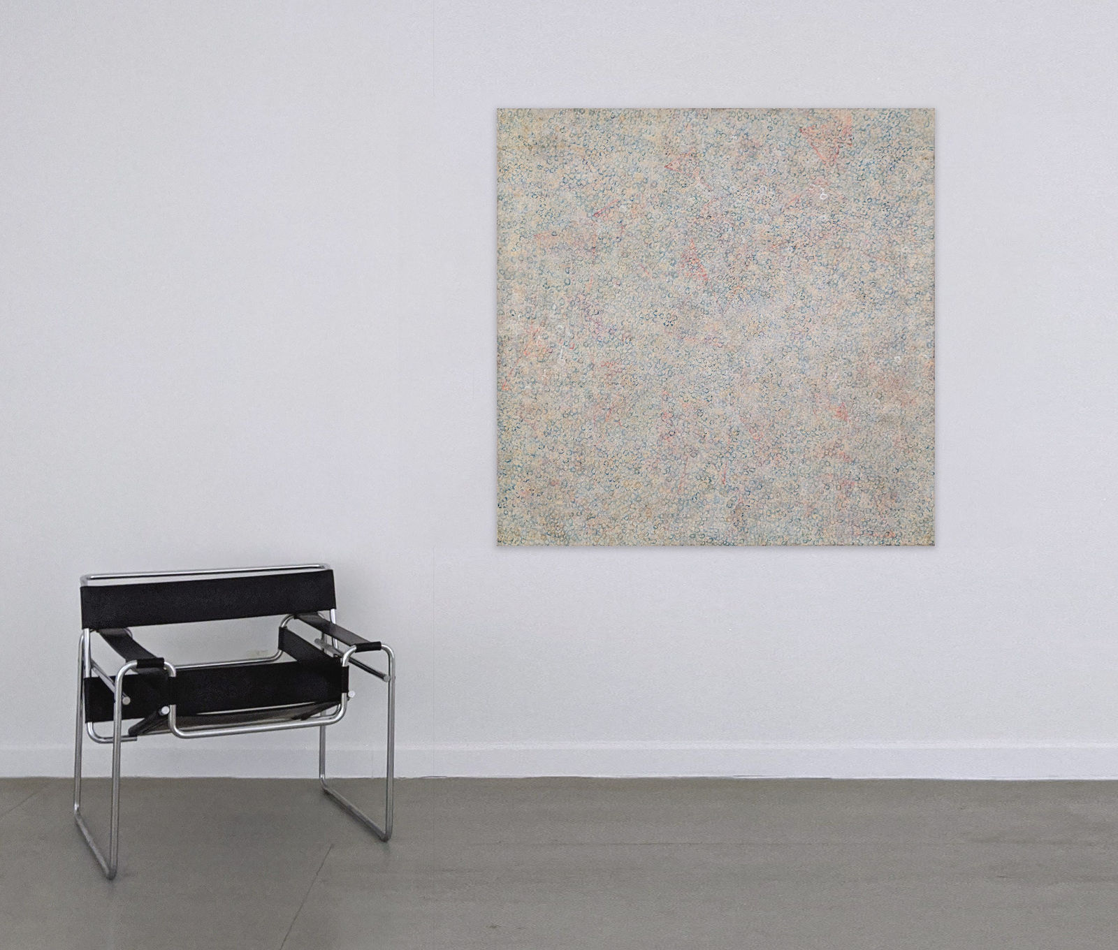 Abstract painting consisting of small marks covering the entire visual field hanging on a wall next to a chair