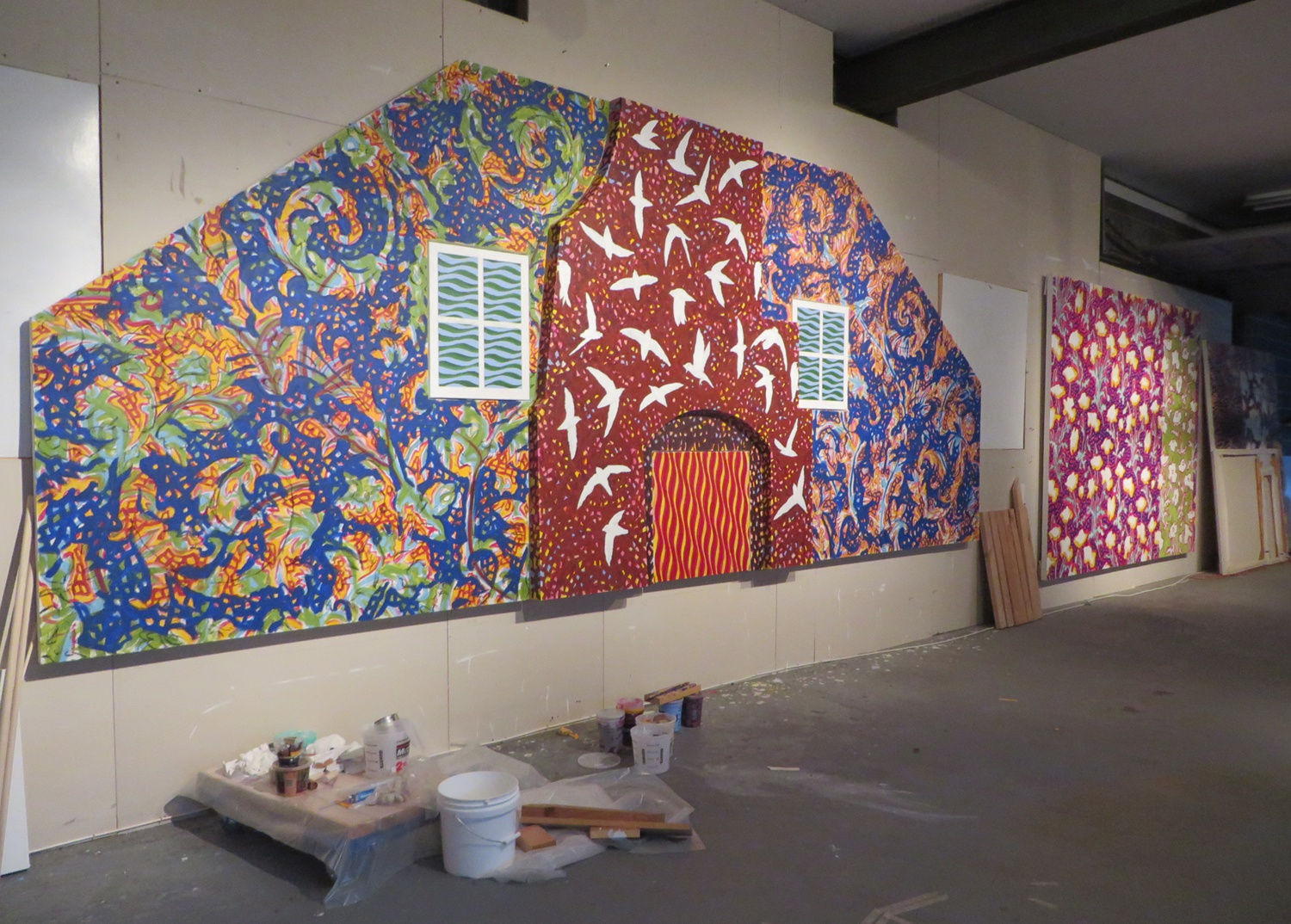 Two brightly-colored paintings with several bright patterns hangs on a beige wall.