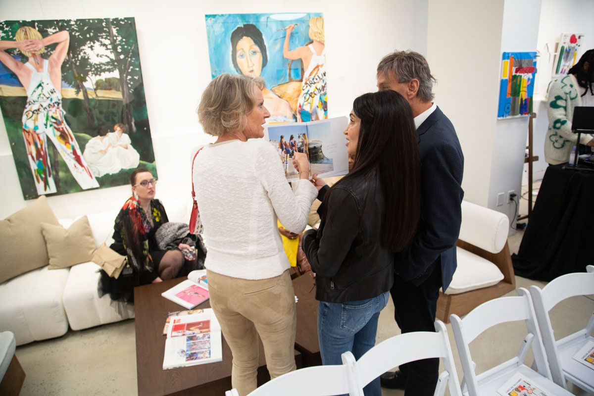 People talking in front of paintings at Carousel Fine Art's gallery space in Buckhead Village, Atlanta during the Caroline Dechamby Retrospective.