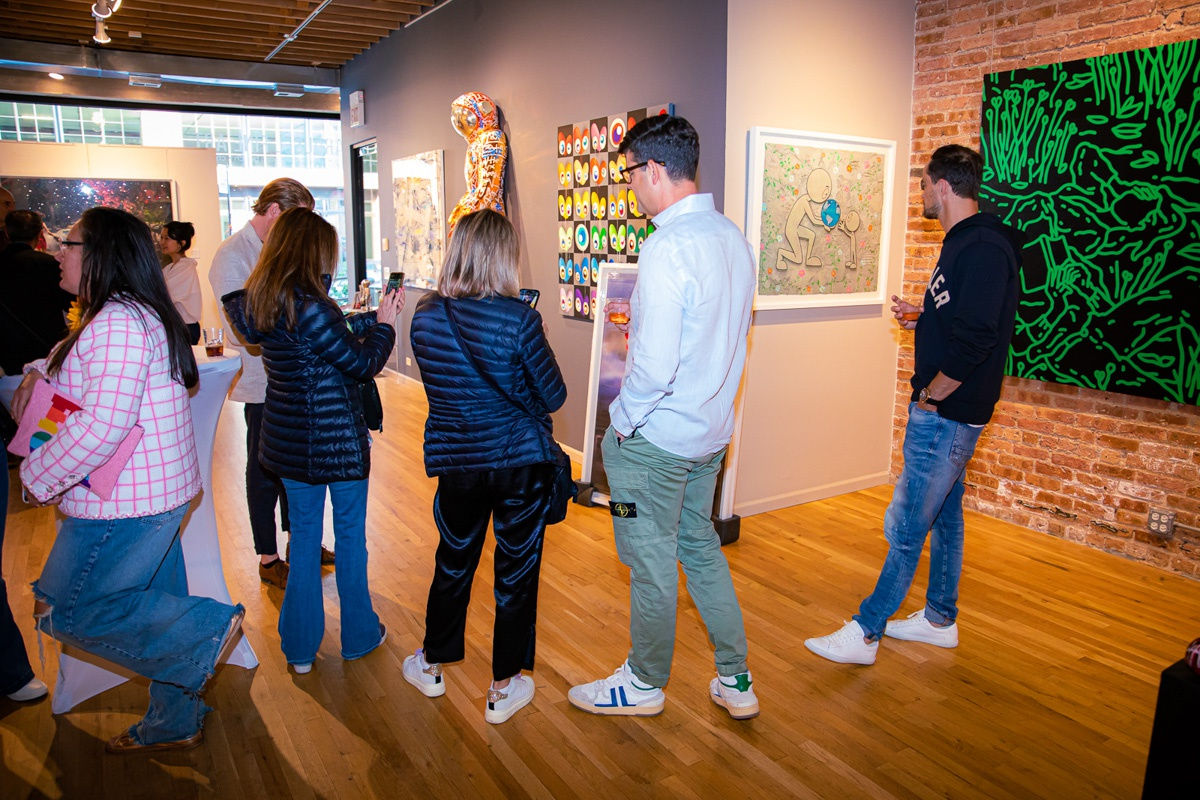 People in Carousel Fine Art's Chicago gallery space staring at paintings displayed.