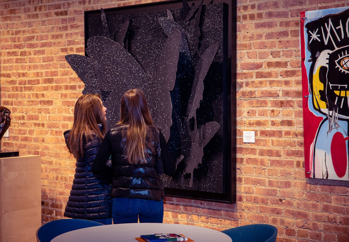 People in Carousel Fine Art's Chicago gallery space staring at paintings displayed.