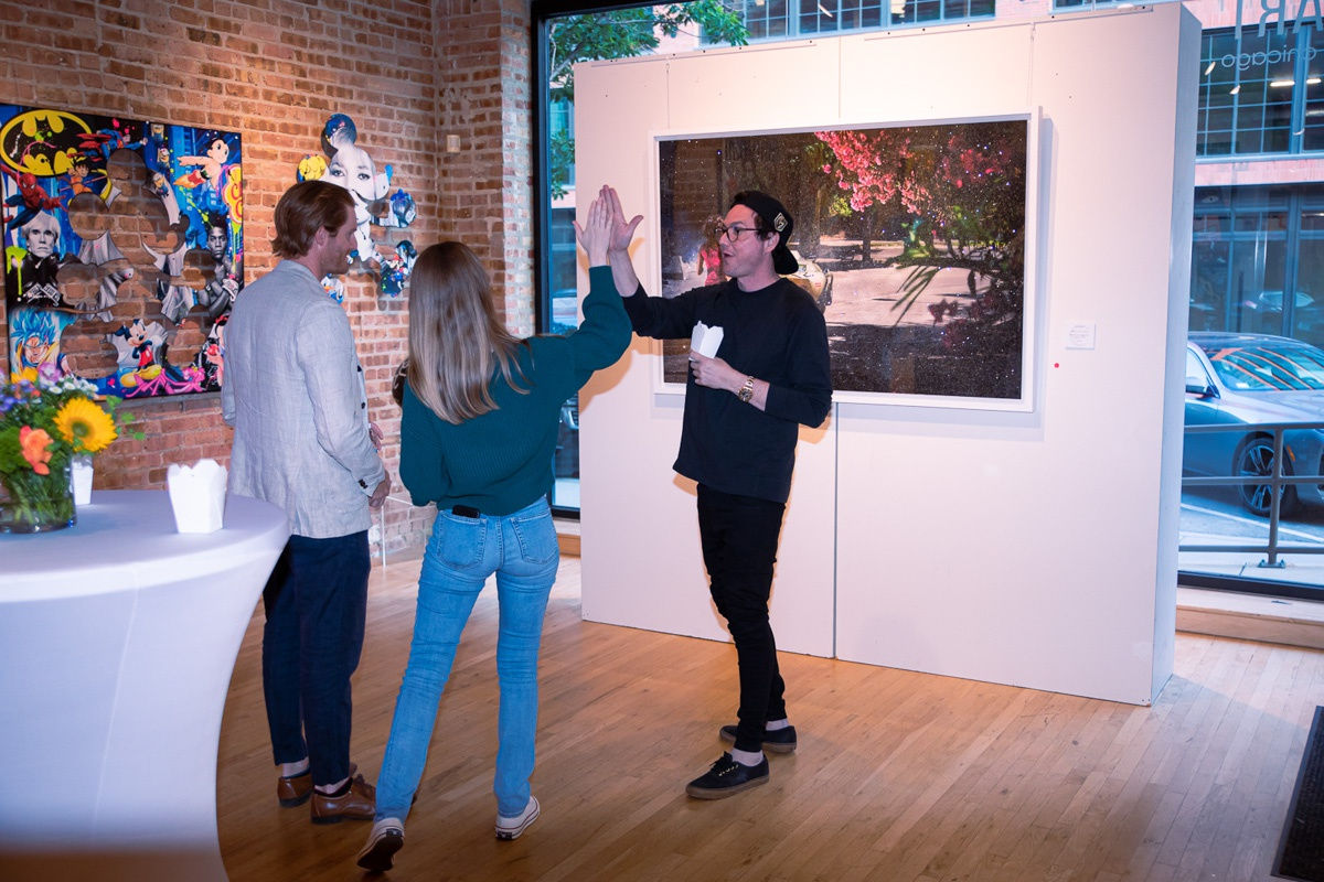 People high-fiving in Carousel Fine Art's Chicago gallery space.