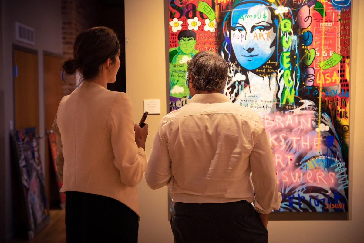 People in Carousel Fine Art's Chicago gallery space staring at paintings displayed.