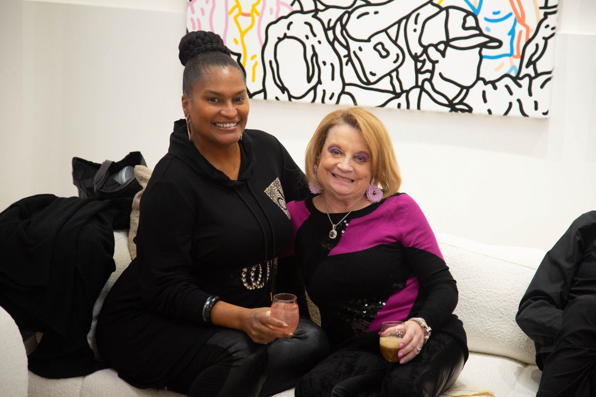 Women posing on couch in Carousel Fine Art's Atlanta gallery space during the spotlight exhibition for John Westbay titled "Love, Outside the Lines."