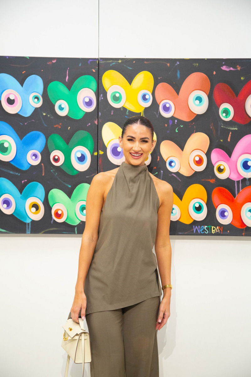 Woman posing in front of painting by John Westbay in Carousel Fine Art's Atlanta gallery space during the spotlight exhibition for John Westbay titled "Love, Outside the Lines."