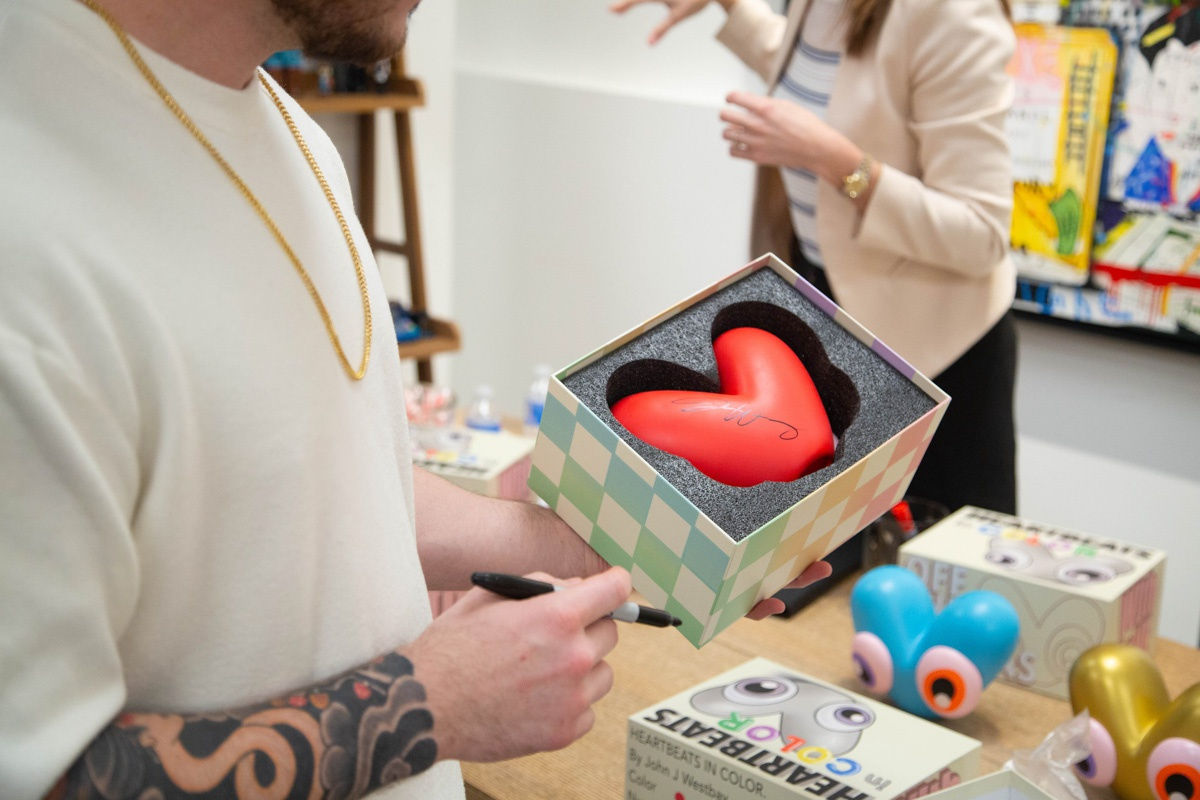 Artist John Westbay with heart object during the spotlight exhibition for John Westbay titled "Love, Outside the Lines."