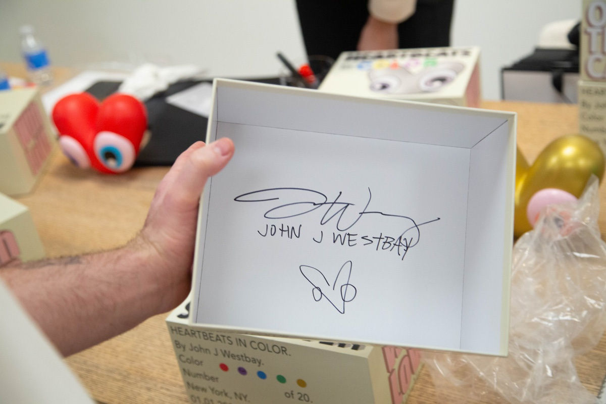 Artist John Westbay signing box during the spotlight exhibition for John Westbay titled "Love, Outside the Lines."