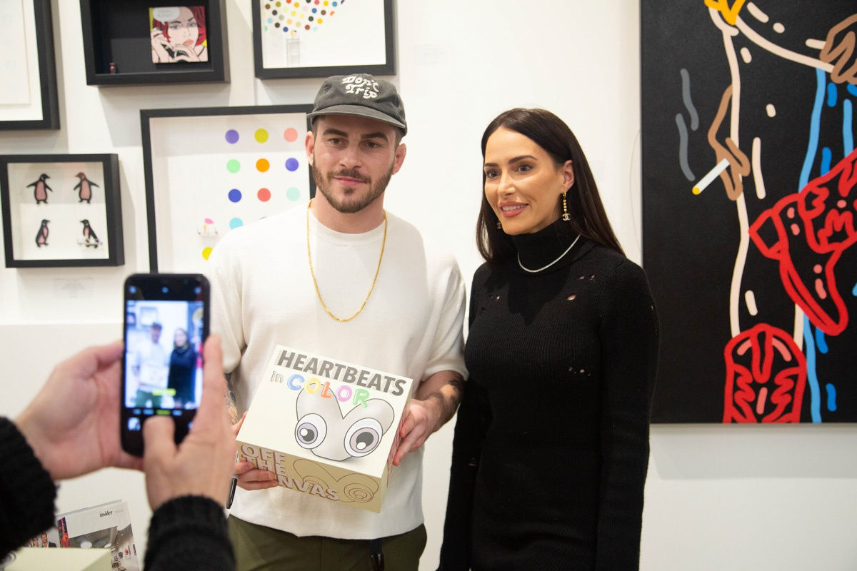 Artist John Westbay posing with woman during the spotlight exhibition for John Westbay titled "Love, Outside the Lines."
