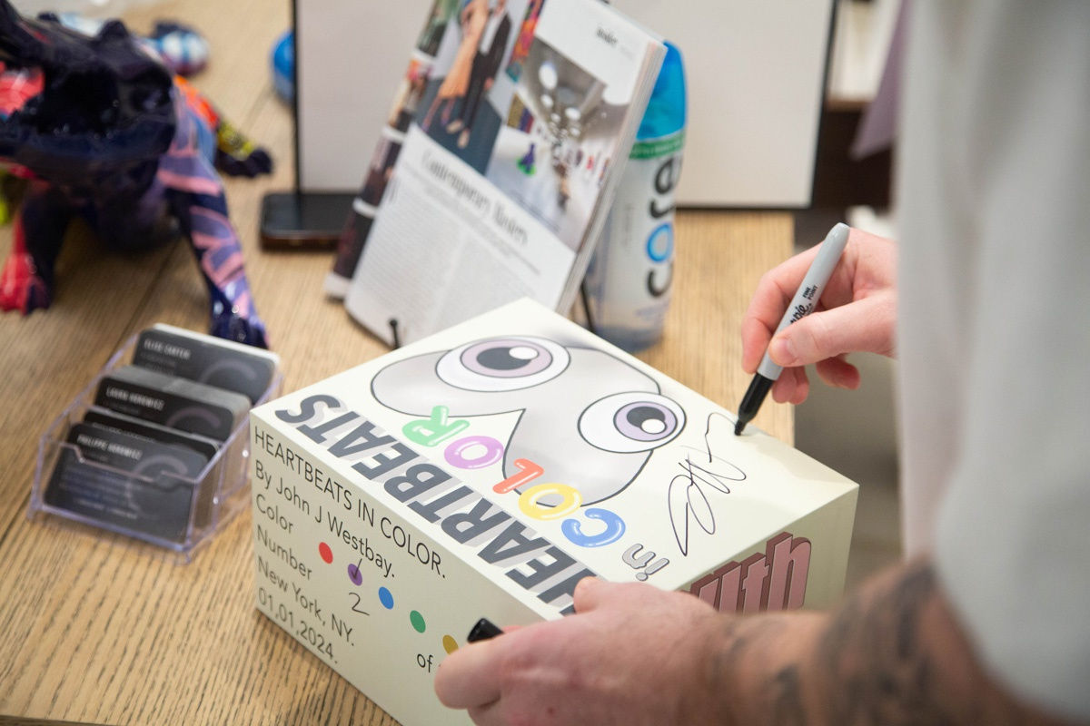 Artist John Westbay signing box during the spotlight exhibition for John Westbay titled "Love, Outside the Lines."