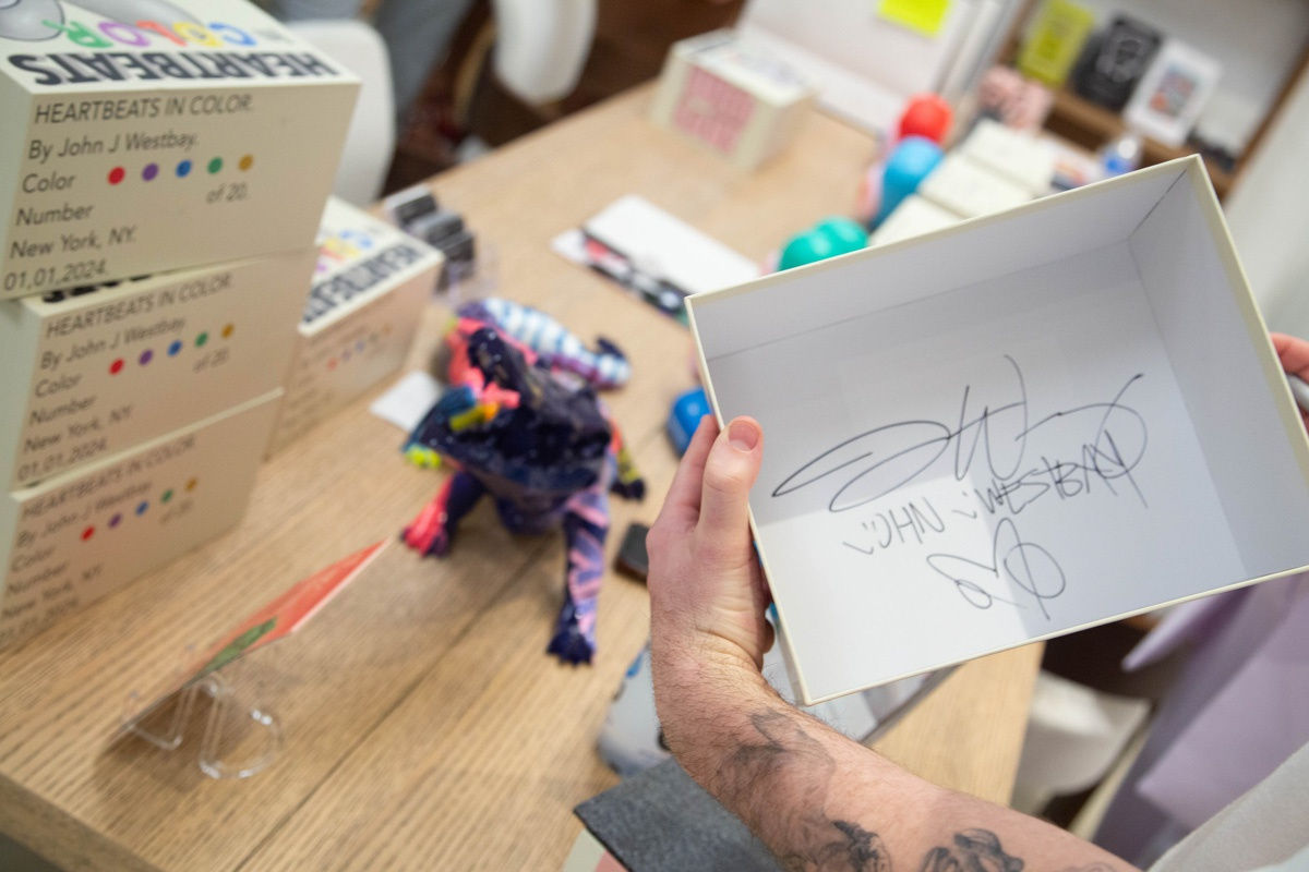 Artist John Westbay signing box during the spotlight exhibition for John Westbay titled "Love, Outside the Lines."