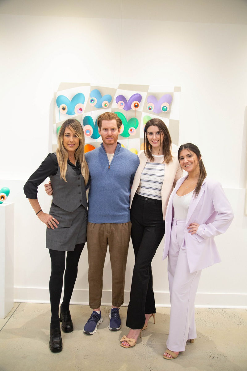 People posing in front of painting by John Westbay in Carousel Fine Art's Atlanta gallery space during the spotlight exhibition for John Westbay titled "Love, Outside the Lines."