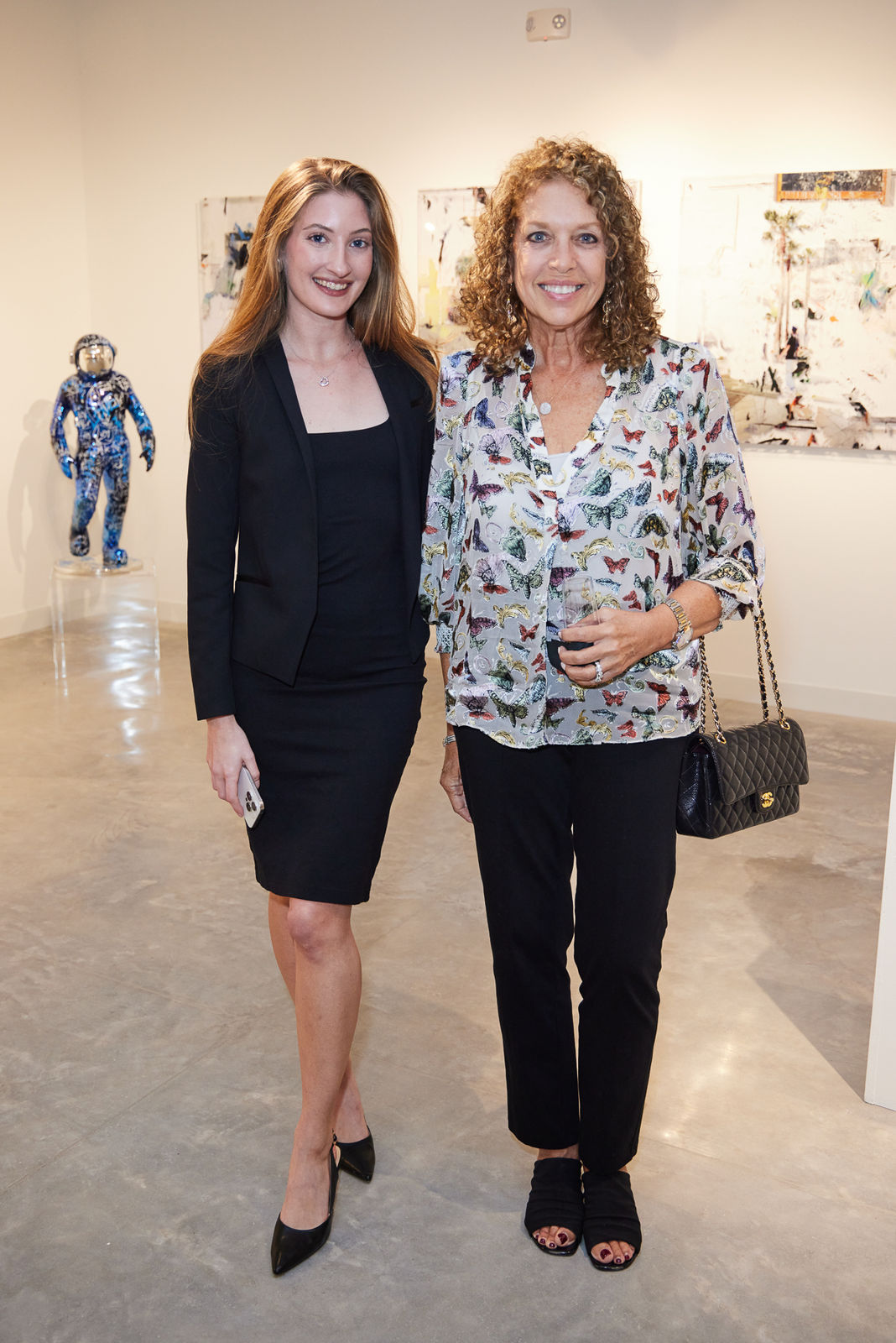 Advisor and client standing side by side beneath a feature wall of mixed contemporary art at NORA District gallery.