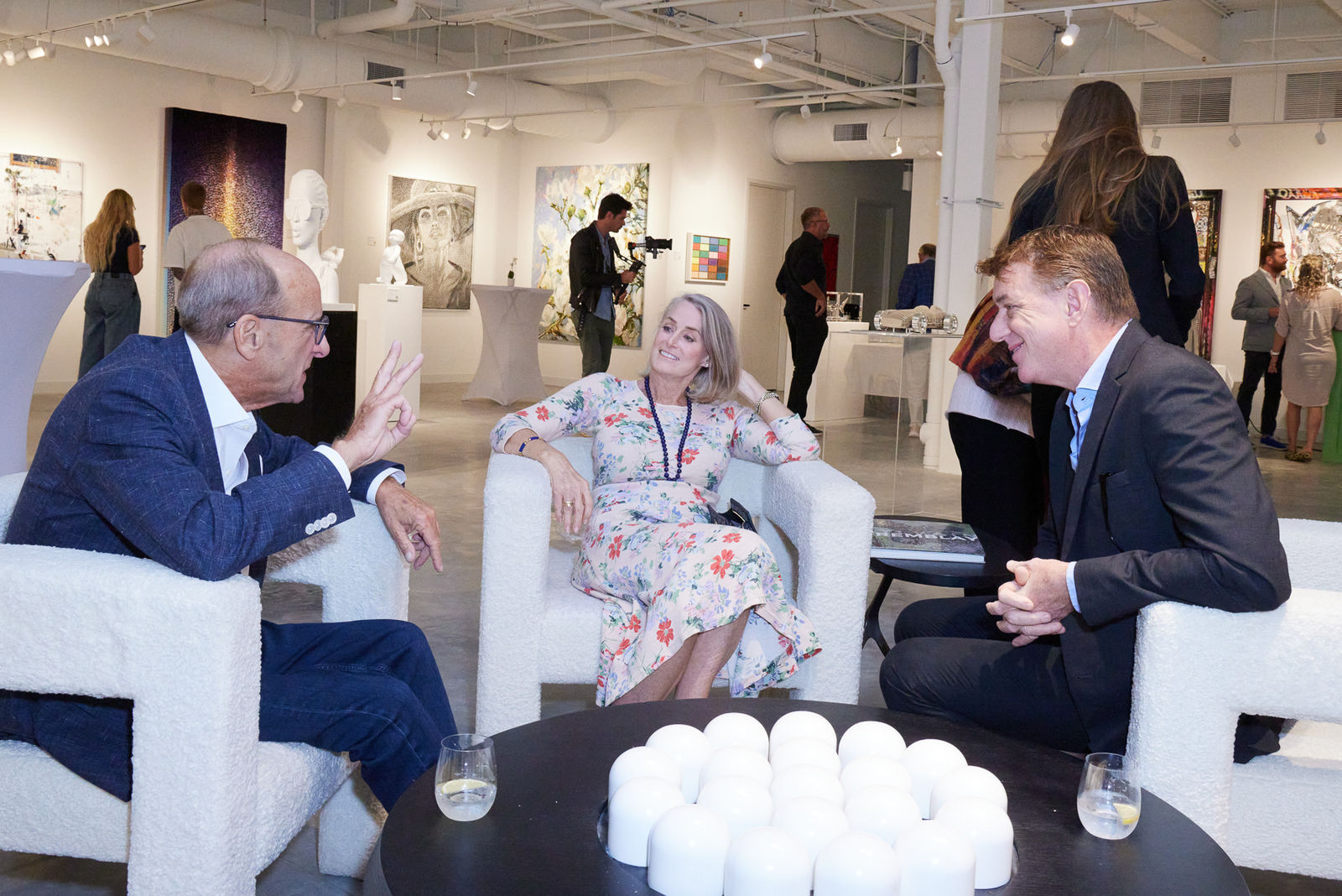 Guests lounging near colorful Zhuang Hong Yi floral piece with NORA District warehouse windows behind them.