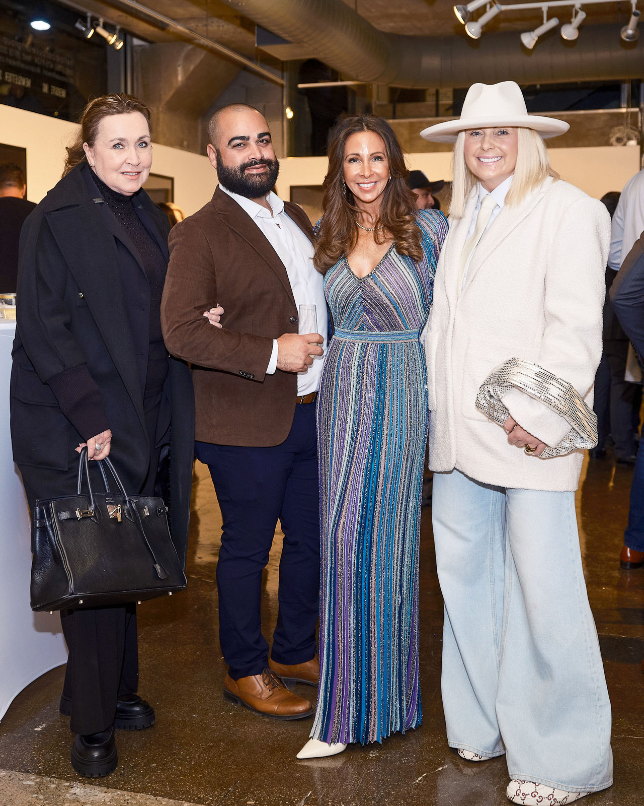Four guests lined up for a posed photo surrounded by Jason M. Peterson monochrome architectural works.